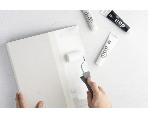 Person streicht eine Platte mit einem Farbroller und Farbe von Do it