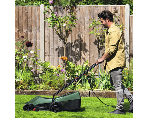 Ein Mann benutzt einen Rasenlüfter im Garten.