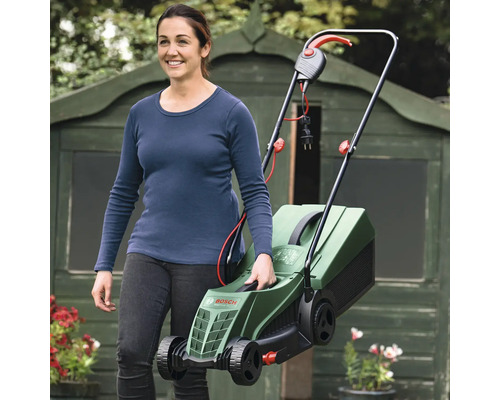 Frau mit Bosch Rasenmäher vor Gartenhaus