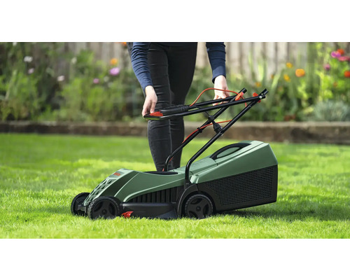 Eine Person bereitet einen grünen Rasenmäher für die Gartenarbeit vor.