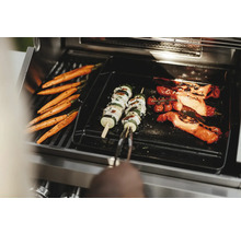 Des légumes tels que des carottes, des brochettes de courgettes et des tomates sont préparés sur un grill.