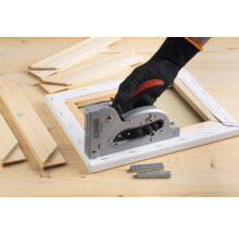 Hand mit Handschuh benutzt einen Handtacker an einer Leinwand