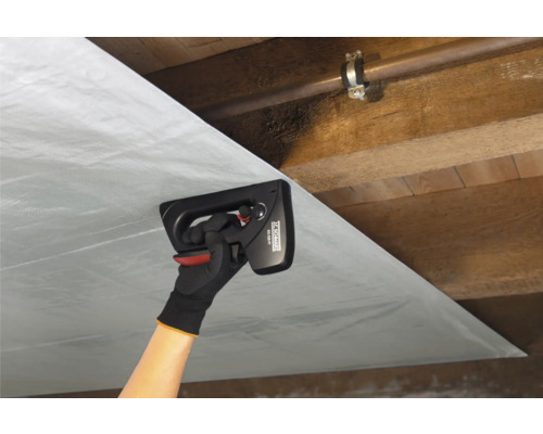 Eine Person befestigt Dampfsperrfolie mit einem Handtacker an einer Holzdecke.