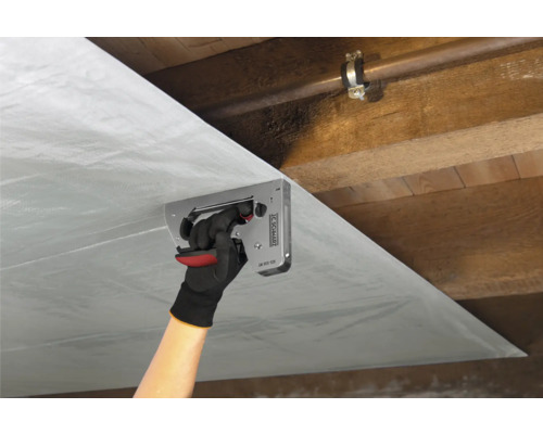 Person befestigt Dampfbremsfolie mit einem Tacker an einer Holzdecke.