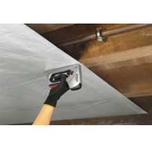Eine Person befestigt eine Folie mit einem Handtacker an einer Holzdecke.