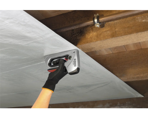 Eine Person befestigt eine Folie mit einem Handtacker an einer Holzdecke.