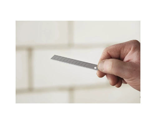 Hand hält eine Trapezklinge für ein Cuttermesser.