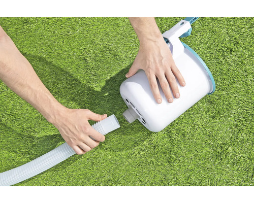 Une personne connecte un écumeur de piscine à un tuyau.