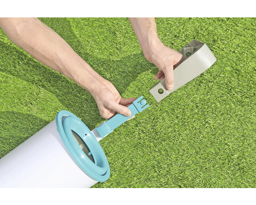 Personne assemblant une échelle de piscine sur une pelouse.