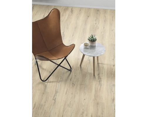 Helles Zimmer mit Sessel, Beistelltisch und Topfpflanze auf Holzboden