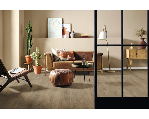 Wohnzimmer mit Sofa, Sessel, Tisch, Stehlampe, Kommode, Dekoration und Zimmerpflanzen auf Holzboden.