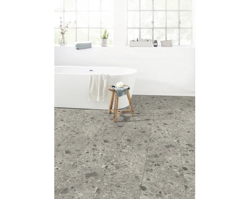 Salle de bains avec baignoire îlot, tabouret en bois et carrelage au sol aspect pierre