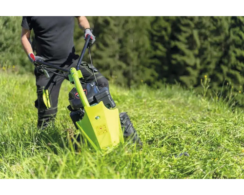 Mann bedient einen Wiesenmäher auf einer Wiese.