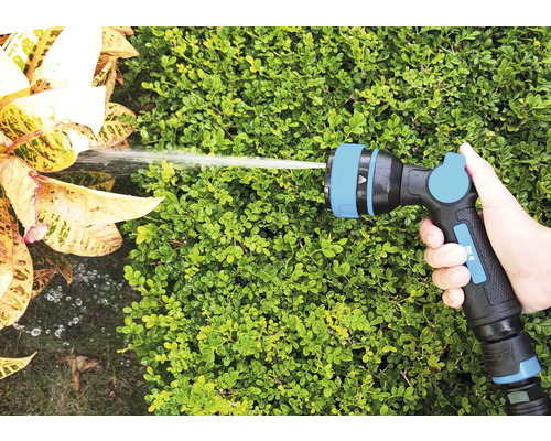 Main tenant un pistolet d''arrosage de tuyau d''arrosage arrosant des plantes