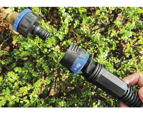 Raccord rapide pour tuyau d''arrosage devant des feuilles vertes