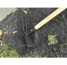 Outil de jardin avec manche en bois et tête en métal dans la terre