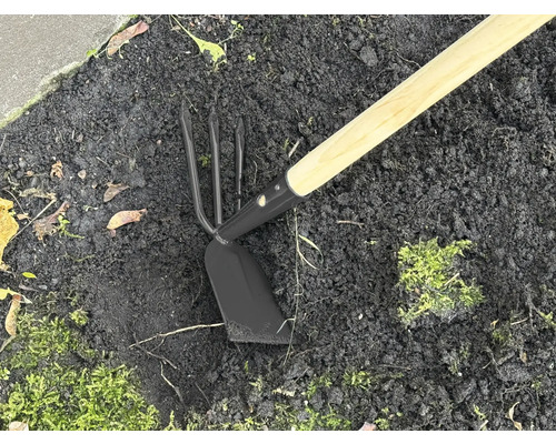 Outil de jardin avec manche en bois et tête en métal dans la terre