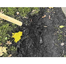 Sarcloir de jardin avec manche en bois en utilisation sur terre noire