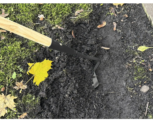 Sarcloir de jardin avec manche en bois en utilisation sur terre noire