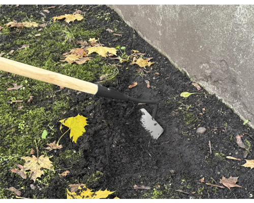 Houe de jardin avec manche en bois utilisée dans le sol du jardin.