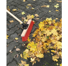 Balai avec manche en bois et feuilles d''automne sur pavés