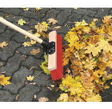 Balai de voirie avec manche en bois et feuilles d''automne sur pavés
