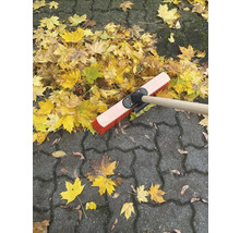 Balai à feuilles sur pavés avec feuilles d''automne
