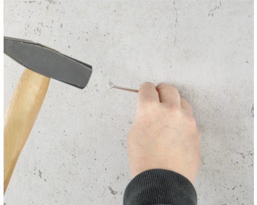 Une personne enfonce un clou dans le mur avec un marteau.