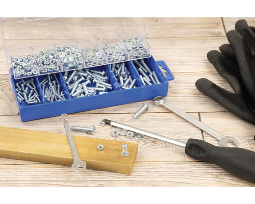 Sortimentskasten mit Schrauben und Muttern, Schraubenschlüssel, Schraubendreher und Handschuhe auf einem Holztisch