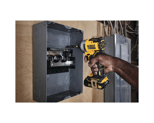 Ein Mann befestigt mit einem Akku-Schlagschrauber einen Sicherungskasten an der Wand.