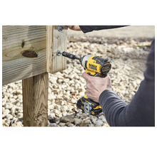 Une personne visse une vis dans une planche de bois avec une visseuse à percussion sans fil DeWalt