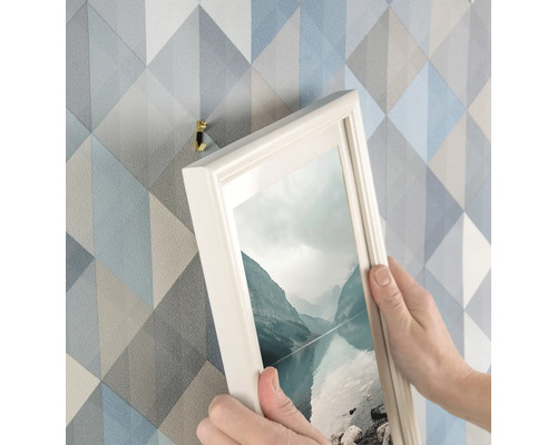 Personne accrochant une photo au mur avec un crochet pour cadre