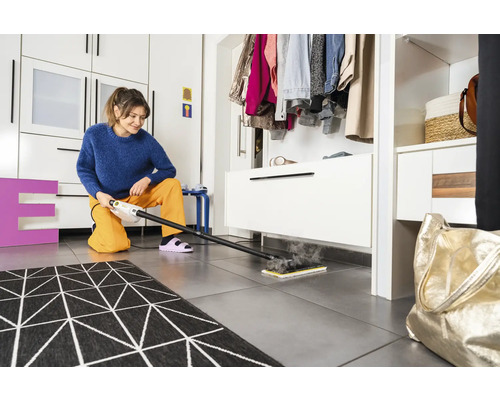 Femme nettoie des carreaux de sol avec un nettoyeur à vapeur dans un couloir avec vestiaire