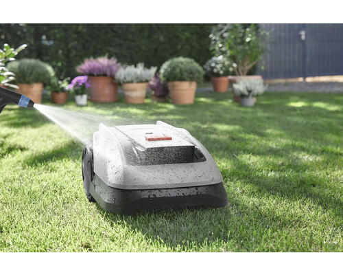 Robot tondeuse à gazon nettoyé à l''eau sur une pelouse avec des fleurs en arrière-plan