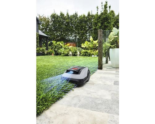 Robot tondeuse à gazon sur pelouse et dalles de pierre
