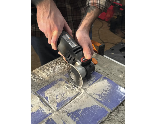Eine Person benutzt ein Multifunktionswerkzeug zum Schneiden von Fliesen.