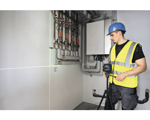 Artisan utilisant un laser linéaire pour l''alignement dans un local de chauffage.