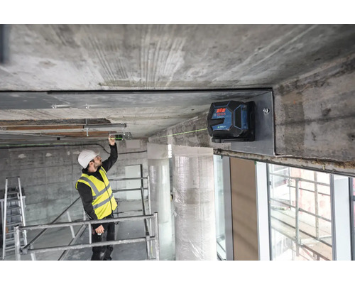 Un ouvrier du bâtiment utilise un laser linéaire pour l''alignement sur un chantier.
