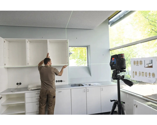 Mann montiert Hängeschrank mit Kreuzlinienlaser in einer Küche.