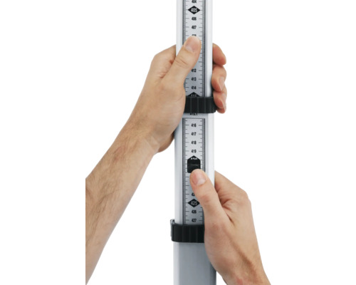 Eine Nivellierlatte wird von zwei Händen gehalten, um eine Höhenmessung durchzuführen.