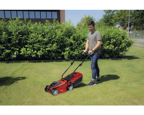 Un homme tond la pelouse avec une tondeuse à gazon dans le jardin.