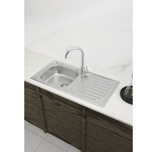 Spüle aus Edelstahl mit Abtropffläche und Wasserhahn auf einer Küchentheke montiert