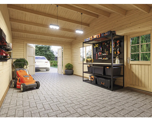 Un garage avec une tondeuse à gazon, une étagère et des outils.