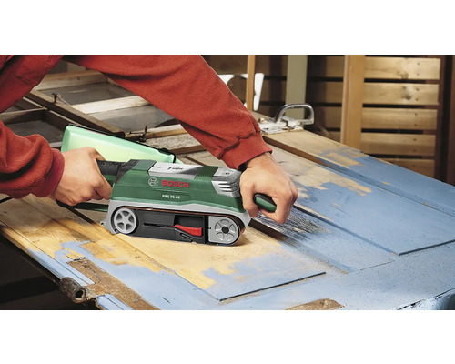 Une ponceuse à bande est utilisée pour poncer une porte en bois.