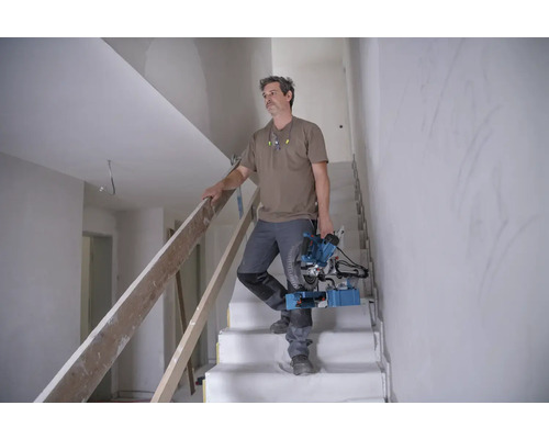 Handwerker mit Kapp- und Gehrungssäge auf einer Treppe im Rohbau