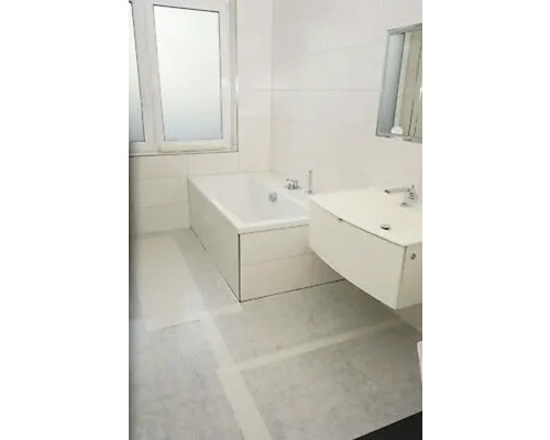 Salle de bain lumineuse avec baignoire et lavabo.