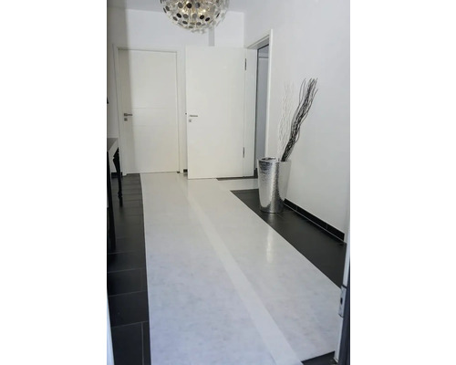 Couloir avec portes blanches, vase argentée et branches décoratives.