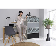 Ein helles Büro mit einem Aktenschrank mit Blattmuster, einem Schreibtisch und einer Frau, die telefoniert.