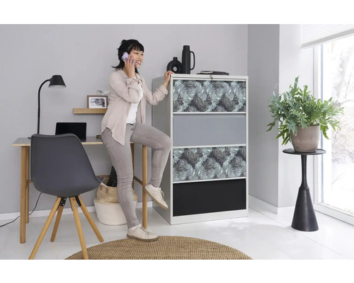 Ein helles Büro mit einem Aktenschrank mit Blattmuster, einem Schreibtisch und einer Frau, die telefoniert.