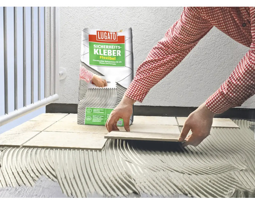 Une personne pose du carrelage avec de la colle à carrelage de la marque Lugato.